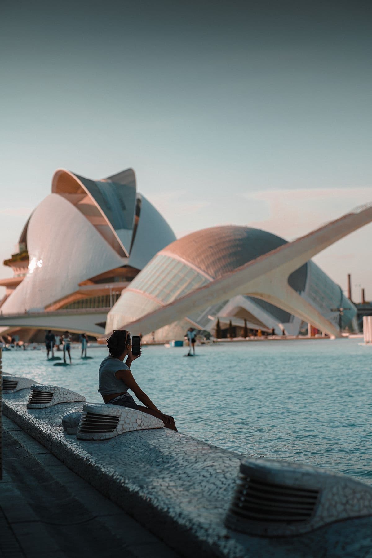 A person sitting by a reflecting pool among the white, futuristic curves of Valencia's City of Arts and Sciences